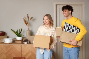 Taşınırken odada karton kutuları olan genç bir çift.