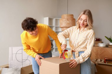 Genç çift taşınma gününde odada karton kutu kaydediyor.