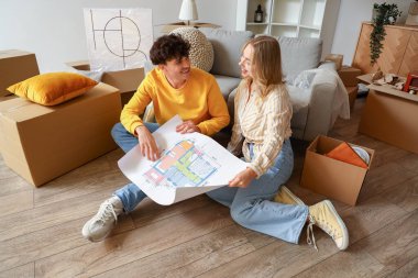 Ev planları olan genç bir çift taşınma gününde odada oturuyor.