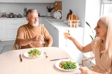 Olgun bir çift mutfakta yemek yiyor.