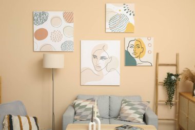 Modern oturma odası içi gri kanepe ve posterlerle dolu.