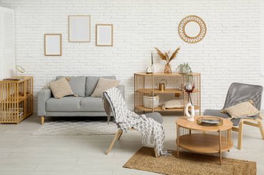 Modern oturma odası içi gri kanepe, koltuklar ve kahve masasıyla dolu.