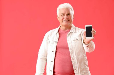 Kırmızı arka planda cep telefonu olan son sınıf öğrencisi.