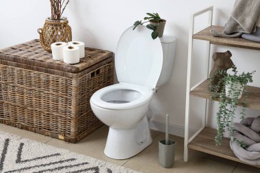 Seramik klozet, raf ünitesi ve hasır sepetli hafif tuvaletin içi.