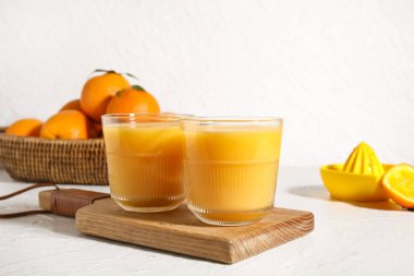 Tahta tahta tahta, beyaz arka planda taze portakal suyu bardakları.