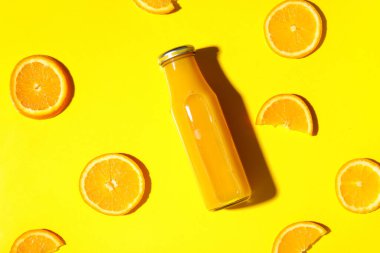 Sarı arka planda bir şişe taze portakal suyu.