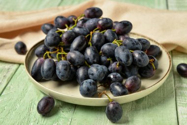 Yeşil ahşap arka planda tatlı siyah üzümlü bir tabak.