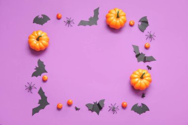 Kabaklardan, yarasalardan ve mor arkaplandaki örümceklerden yapılmış bir çerçeve. Cadılar Bayramı konsepti