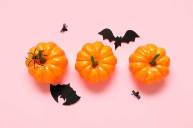 Kabaklarla, yarasalarla ve pembe arka planda örümceklerle kompozisyon. Cadılar Bayramı konsepti