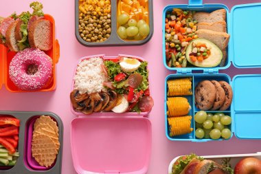 Pembe arka planda farklı lezzetli yemekleri olan bir sürü beslenme çantası.