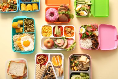 Sönük sarı arka planda farklı lezzetli yemekleri olan bir sürü beslenme çantası.