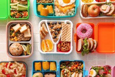 Bej kaplama arka planda farklı lezzetli yemekleri olan bir sürü beslenme çantası.