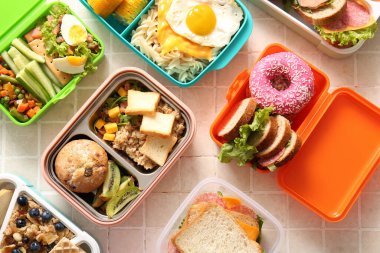 Bej kaplama arka planda farklı lezzetli yemekleri olan bir sürü beslenme çantası.