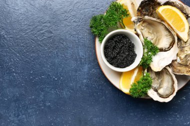 Lezzetli istiridye tabağı ve mavi arka planda siyah havyar.