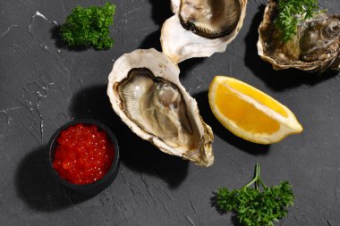 Limonlu lezzetli istiridye ve siyah arka planda kırmızı havyar.