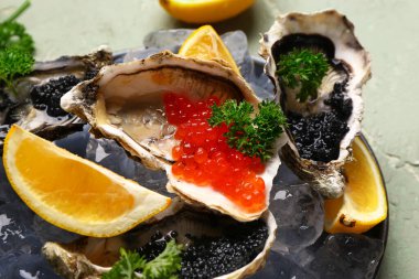 Limonlu lezzetli istiridye tabağı, gri arka planda siyah ve kırmızı havyar.