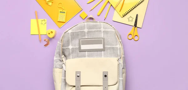 紫丁香背景的学校背包和不同的文具 顶视图 — 图库照片