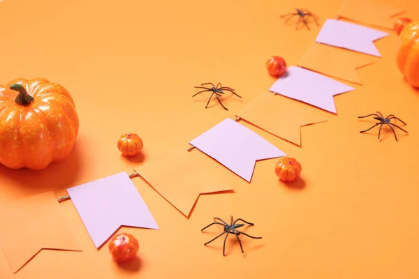 Garland made of paper flags, pumpkins and spiders for Halloween celebration on orange background, closeup