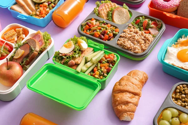 许多午餐盒 背景为紫丁香 有不同的美味食物 — 图库照片