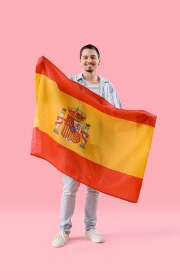 Pembe arka planda İspanya bayrağı taşıyan yakışıklı genç adam.