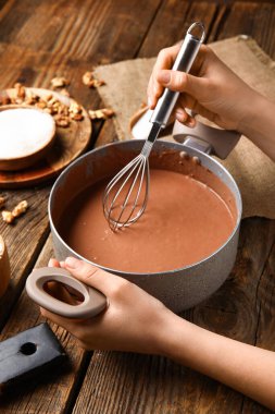 Ahşap arka planda çikolatalı kek için hamur hazırlayan kadın.