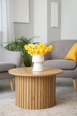 Oturma odasındaki sehpanın üzerinde güzel narsis çiçekleri olan vazo.