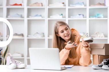 Kadın satıcı ayakkabı dükkanında dizüstü bilgisayarla düzeltme yapıyor.