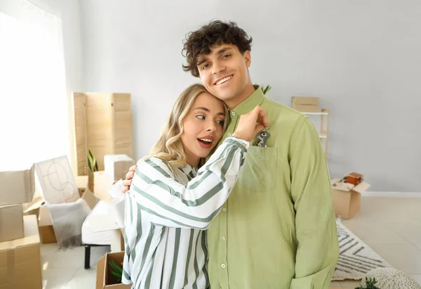 Young couple with keys from their new flat in bedroom on moving day