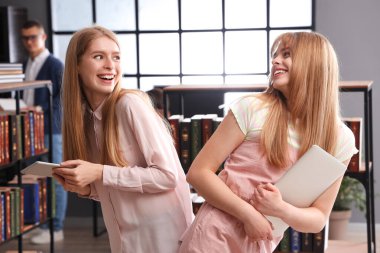 Kütüphanede dizüstü bilgisayarı ve tablet bilgisayarı olan kız öğrenciler