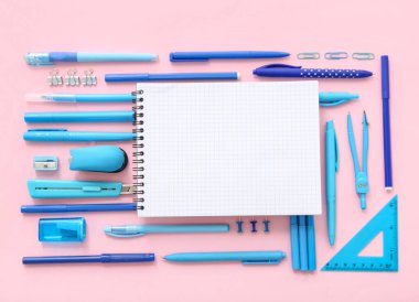 Pembe arkaplanda boş defter ve renkli kırtasiye ile kompozisyon