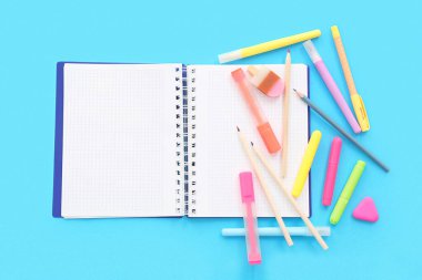 Okul malzemeleriyle kompozisyon ve renk arkaplanı üzerine açık bir defter