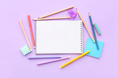 Leylak arkaplan üzerine boş defter ve okul malzemeleri içeren kompozisyon