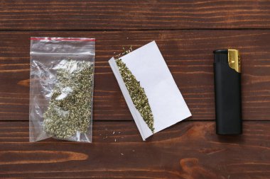 Uyuşturucu dolu plastik torba ve tahta arka planda çakmak.