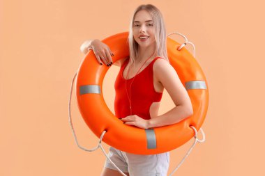 Bej arka planda halka şamandırası olan kadın cankurtaran.