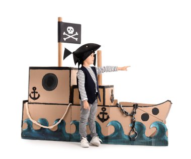 Beyaz arka plandaki bir şeyi işaret eden karton gemisi olan sevimli küçük bir korsan.
