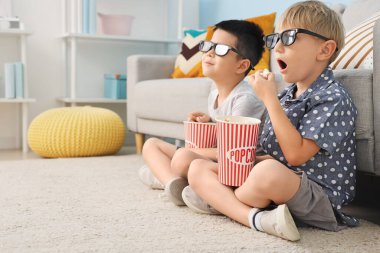 Üç boyutlu gözlüklü, patlamış mısırlı şirin çocuklar evde film izliyor.