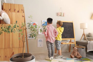Evdeki çizimlerin yanında sevimli küçük çocuklar.