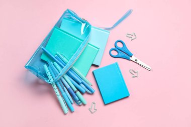 Pembe arka planda farklı okul kırtasiyesine sahip kalem kutusu.