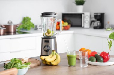 Mutfaktaki masada karıştırıcı ve bir bardak sağlıklı smoothie.