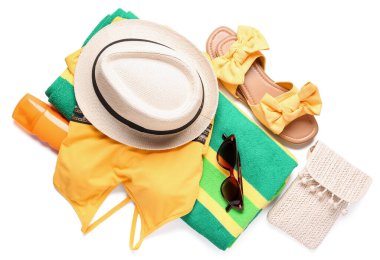 Havalı plaj şapkası, parmak arası terlik, bikinili sütyen, güneş gözlüğü, beyaz arka planda bir şişe güneş kremi ve havlu.