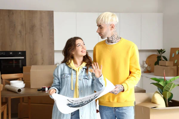Young couple with house plan in kitchen on moving day