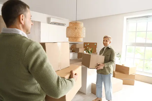 Mature couple with cardboard boxes in kitchen on moving day