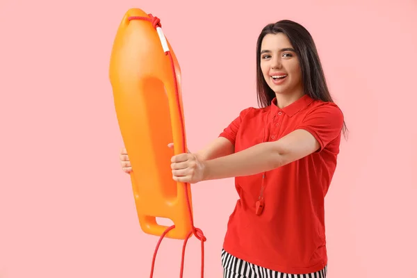 Female lifeguard with board on pink background