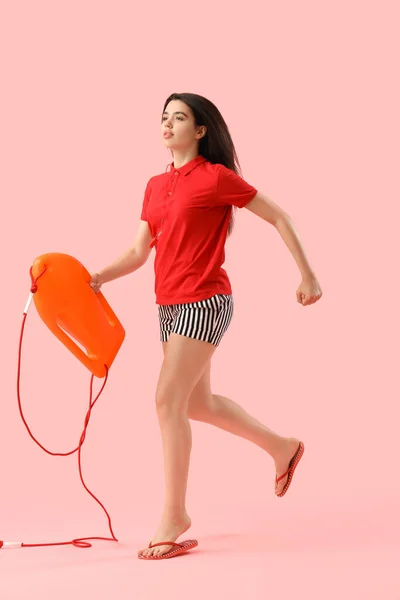 Female lifeguard with board running on pink background