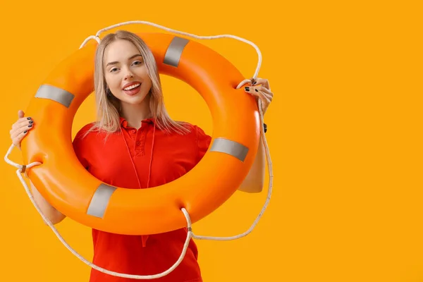 Female lifeguard with ring buoy on yellow background