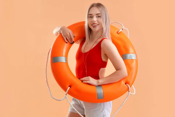 Female lifeguard with ring buoy on beige background