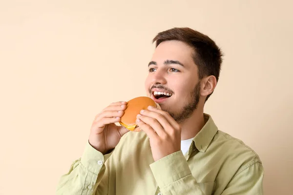 Tânărul Mănâncă Burger Gustos Fundal Bej Closeup — Fotografie, imagine de stoc