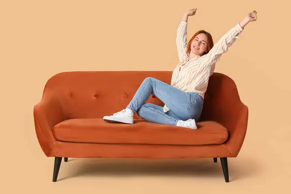 Young woman resting on sofa against beige background