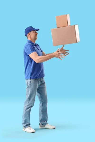 Reifer Kurier Wirft Pakete Auf Blauem Hintergrund — Stockfoto