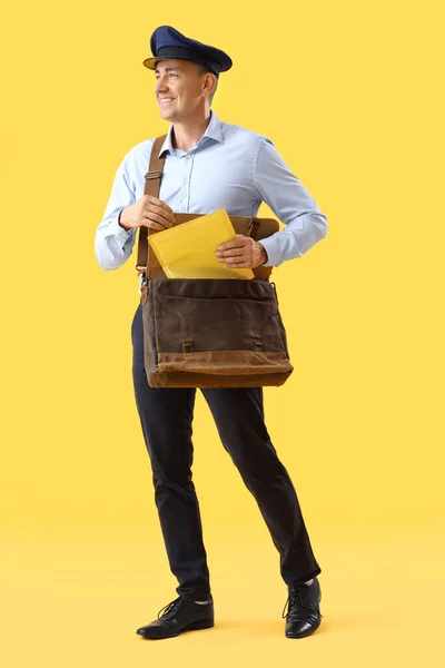 成熟したポストマンと黄色の背景にバッグと封筒 — ストック写真
